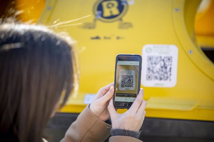 Una usuaria de RECICLOS escanea el código QR del contenedor amarillo.