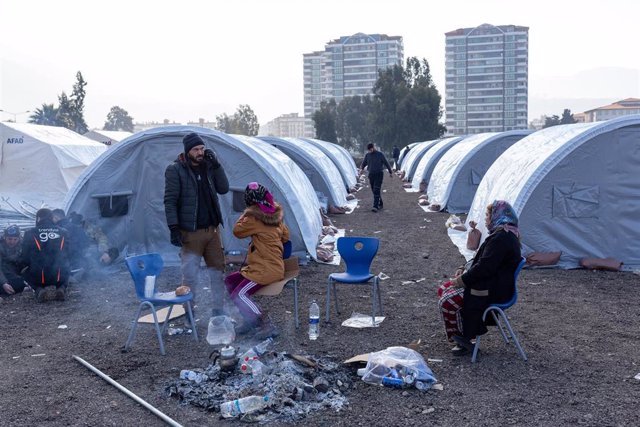 Varias personas permanecen en una ciudad de tiendas de campaña creada para las víctimas del terremoto en el distrito de Iskenderun de Hatay, donde muchos edificios quedaron destruidos tras el devastador seísmo  a lo largo de la frontera turco-siria