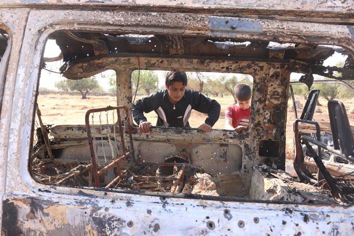 Archivo - 27 October 2019, Syria, Barisha: Syrian children inspect a burnt vehicle at the site near the northwestern Syrian village of Barisha in the province of Idlib near the border with Turkey, after media reports said Islamic State (IS) leader Abu B