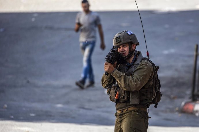 Archivo - 28 September 2022, Palestinian Territories, Hebron: An Israeli soldier aims his weapon during clashes with Palestinian protesters in the West Bank city of Hebron. Protests and clashes have erupted in the West Bank following the killing of at l