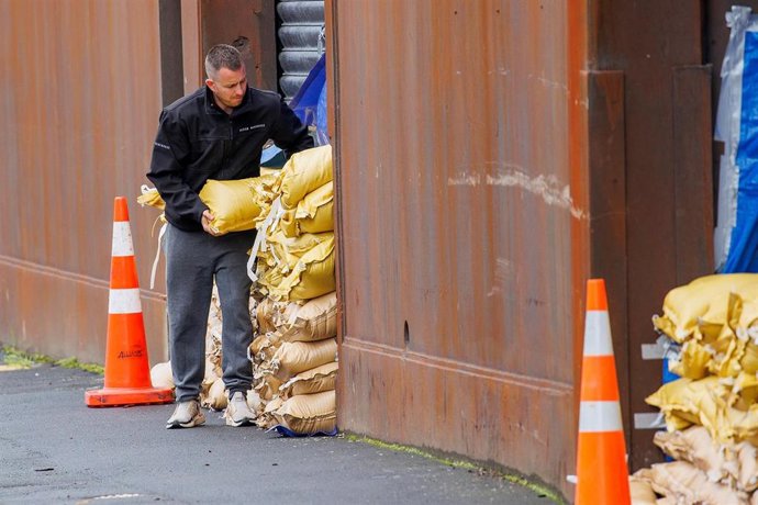 Un hombre coloca sacos frente a un almacén ante las inundaciones previstas por la llegada del ciclón 'Gabrielle' a Nueva Zelanda