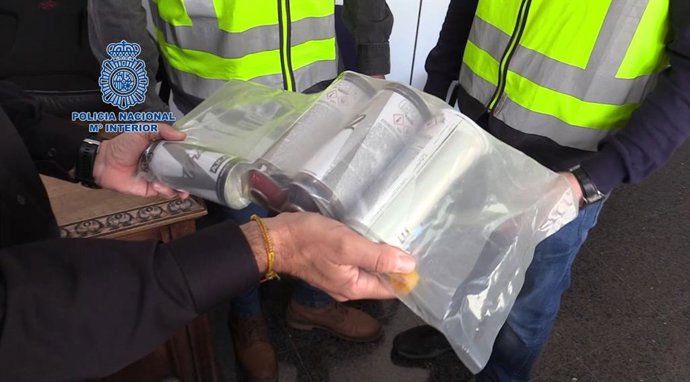 Un agente sostiene varios botes de pintura para grafitis.