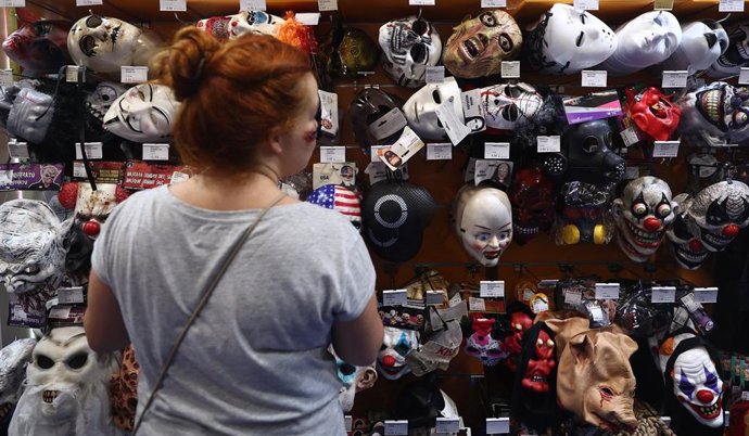 Archivo - Una mujer observa caretas en una tienda