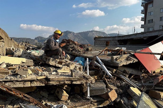 Un rescatista sentado sobre los escombros de un edificio derrumbado por el terremoto en Hatay, Turquía