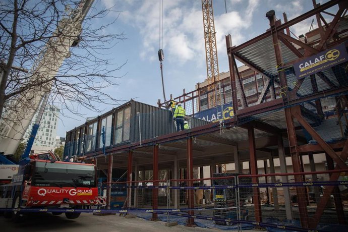 Archivo - Operarios descargan contenedores marítimos para construir un edificio de alojamientos.