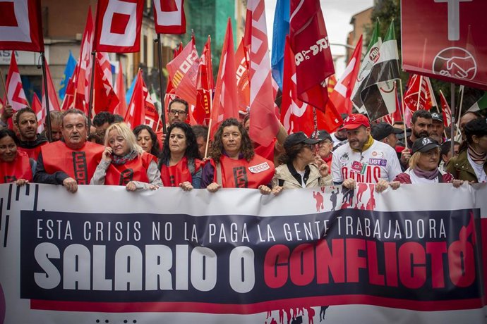 Archivo - Un grupo de personas sostiene banderas y una pancarta durante una movilización convocada por CCOO y UGT desde Puerta de Toledo,  