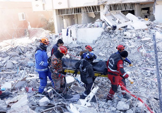 13 February 2023, Turkey, Gaziantep: Rescue workers of the Malaysian National Disaster Management Agency (NADMA) and local relief forces recover a body from a destroyed building after the deadly earthquake that struck Turkey and Syria. Photo: Hairul/BER