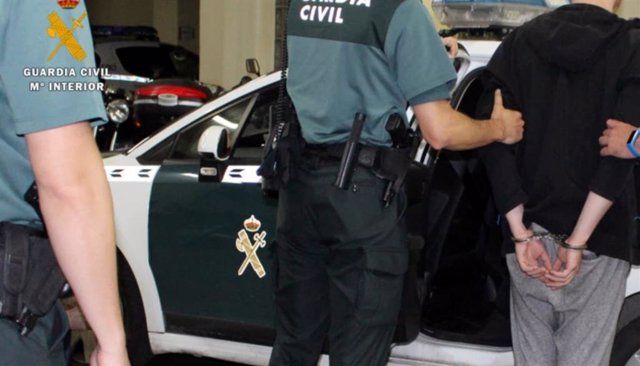 Un agente de la Guardia Civil acompaña a un detenido.