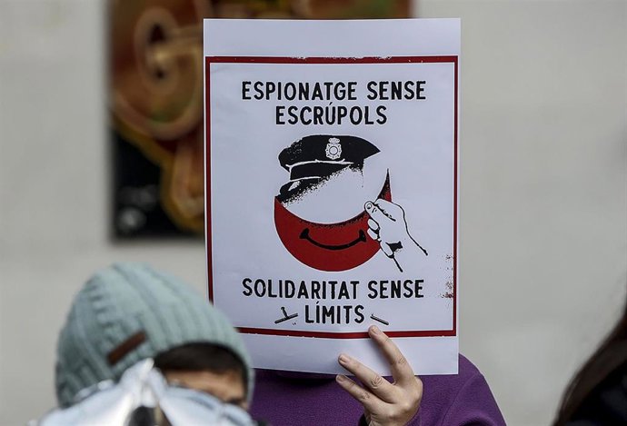 Una mujer sujeta un cartel que hace referencia al espionaje, durante una rueda de prensa de miembros de los movimientos vecinales CSOA l'Horta, Cuidem Benimaclet y Alerta Solidria.