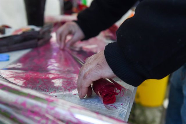 Un empleado prepara una rosa en una floristería por el día de San Valentín.