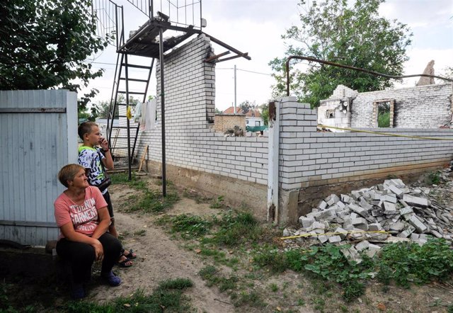 Archivo - Una mujer y un niño miran su casa en ruinas destruida por los militares rusos en el pueblo de Andrivka, en la región de Kiev