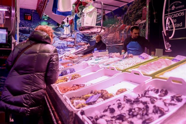Archivo - Una mujer realiza sus últimas compras de pescado y marisco 