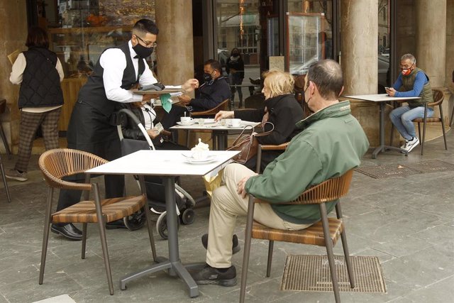 Archivo - Un camarero atiende a varios clientes en la terraza de un bar en Palma.