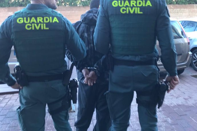 Dos agentes de la Guardia Civil llevan a uno de los detenidos.