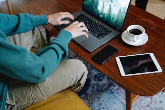 Archivo - Un hombre utilizando un ordenador, un móvil y una tableta.