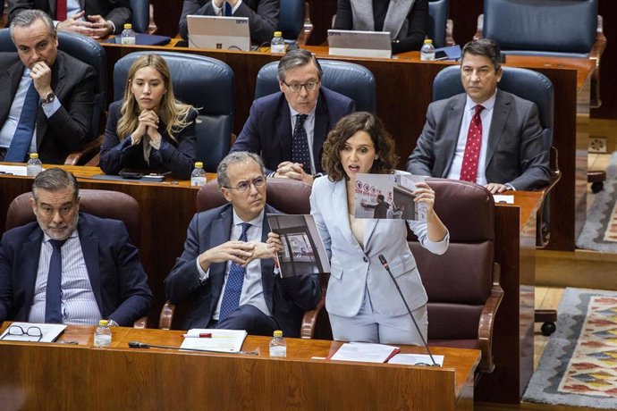 Isabel Díaz Ayuso sostiene una foto del candidato de Podemos al Ayuntamiento de Madrid, Roberto Sotomayor, y a la portavoz de esta formación en la Cámara regional, Carolina Alonso, colgando carteles a las puertas de un centro de salud
