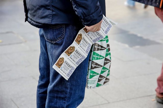 Archivo - Un hombre sostiene cinco décimos de lotería