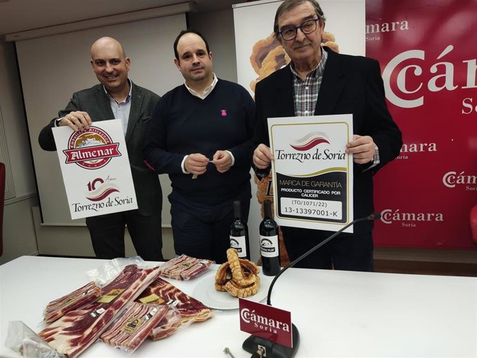 De izda a dcha, Delgado, Rebollar y Moreno pegan la etiqueta de Marca de Garantía Torrezno de Soria.