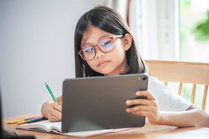 Archivo - Niña con gafas, tarea, tablet, colegio.