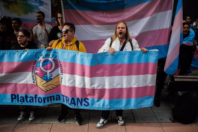 Varias personas con una banderas trans durante una concentración de la Federación Plataforma Trans, en la sede del PSOE en la calle Ferraz, a 28 de octubre de 2022, en Madrid (España), 