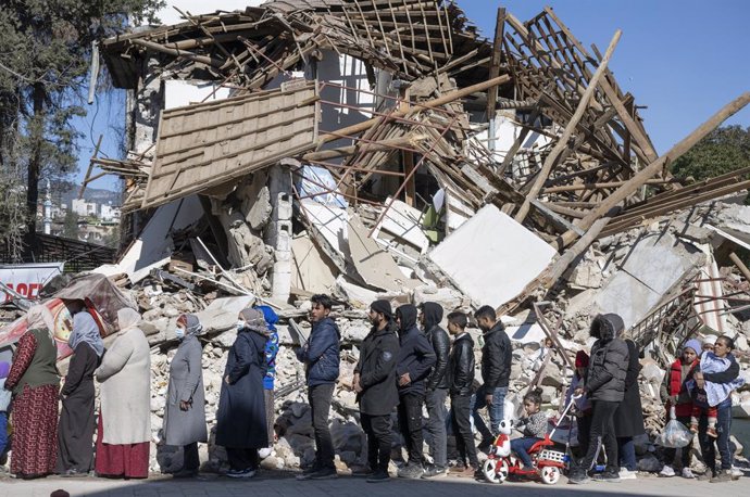 Un grupo de damnificados por los terremotos en Turquía hace cola para recibir ayuda alimentaria en la localidad de Kirikhan