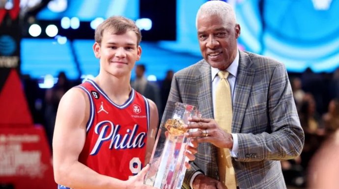 El base de Philadelphia 76ers Mac McClung recibe el trofeo del concurso de mates del All-Star de la NBA de manos de Julius Erving