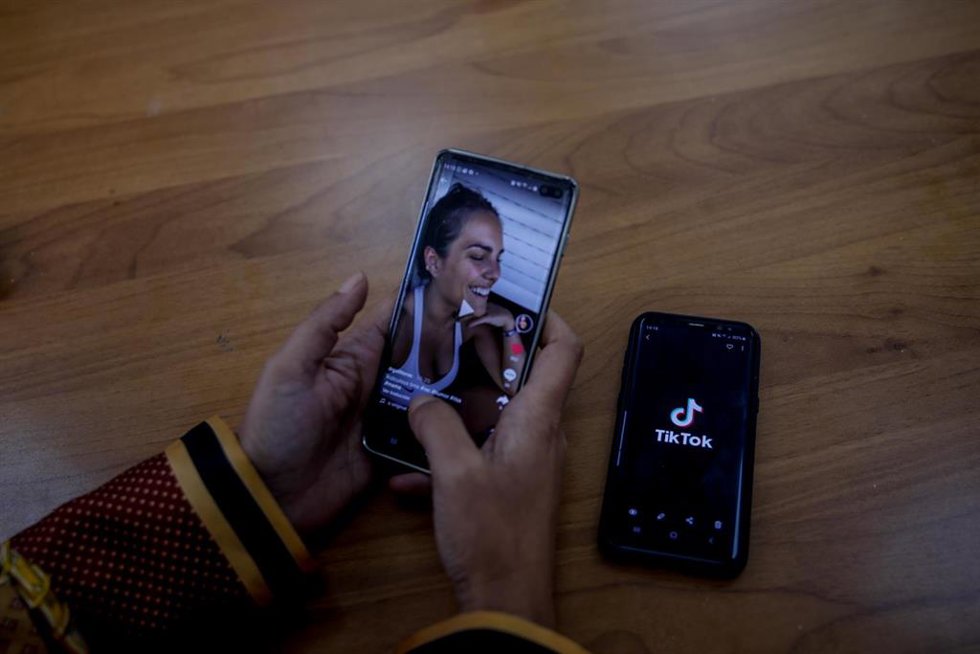 Archivo - Una persona mira en su móvil el vídeo de una joven en la red musical Tik Tok