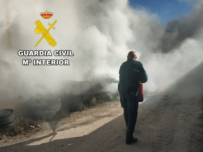 Agente de la Guardia Civil sofocando el incendio de neumáticos