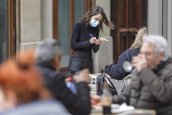 Archivo - Una camarera atiende a varios clientes en una terraza