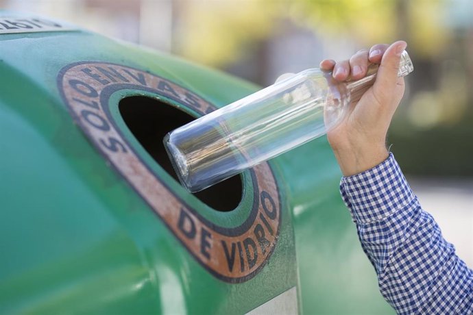 Archivo - Un usuario deposita una botella de vidrio en un contenedor verde