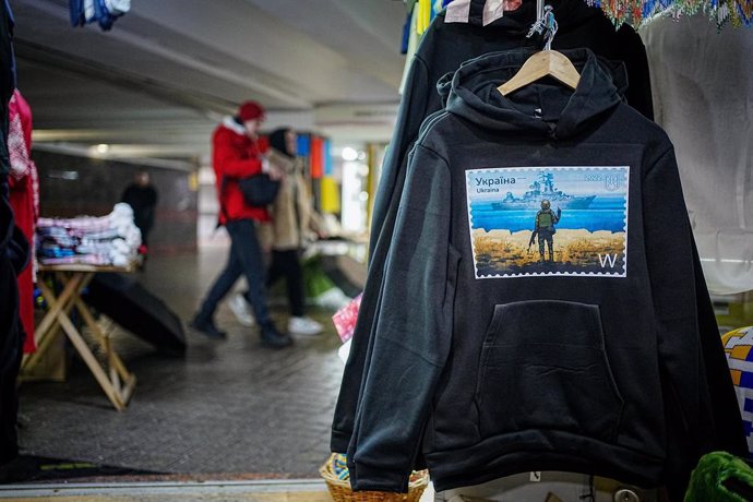 21 February 2023, Ukraine, Kiev: Sweatshirts with imprint of a Ukrainian soldier in front of a Russian warship offered for sale in a souvenir store. Photo: Kay Nietfeld/dpa