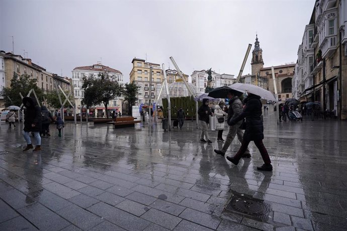 Archivo - Ciudadanos caminan mientras lluev en Vitoria