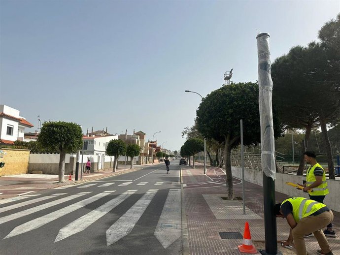 Empleados municipales instalan uno de los pasos de peatones inteligentes en la ciudad de Rota (Cádiz)
