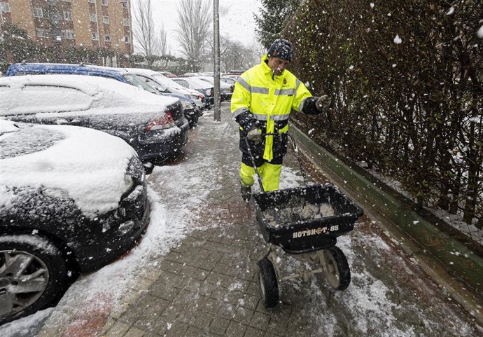 Un operario del Ayuntamiento de Valladolid esparce sal en la acera ante la nevada del 23 de febrero de 2023.