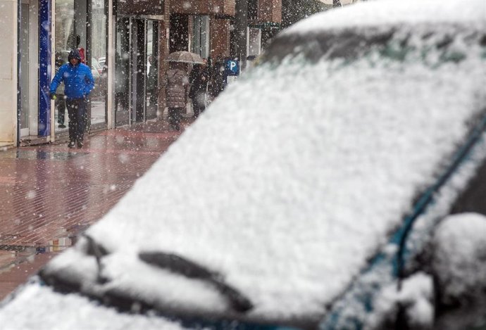 Varias personas caminan por la calle mientras nieva, a 23 de febrero de 2023, en Burgos.