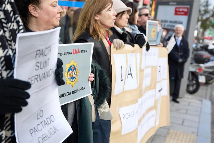 Varios letrados se concentran con carteles y una pancarta mientras tiene lugar una reunión del comité de huelga de los letrados con Justicia.