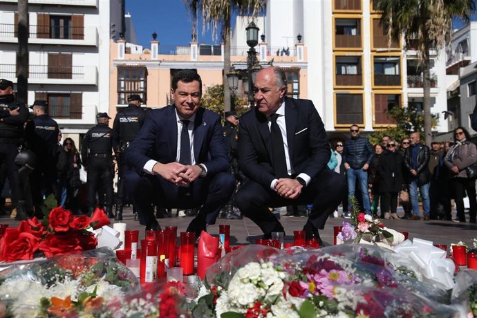 El presidente de la Junta de Andalucía, Juanma Moreno (i) junto con el alcalde de Algeciras, José Ignacio Landaluce, ante las flores y velas dejadas en la plaza en la que ha sido asesinado el sacristán de la Iglesia de La Palma, Diego Valencia. Archivo