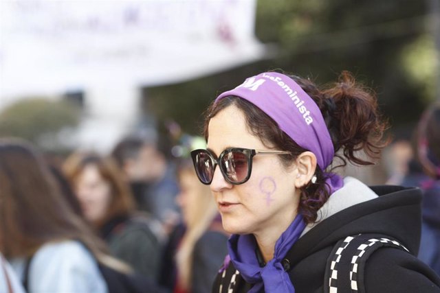Archivo - Una mujer con bandana morada y símbolo de la mujer en la cara en el barrio de Lavapiés durante el 8-M.  