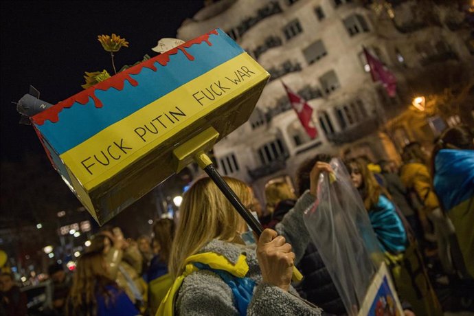 Una mujer sujeta una caja de cartón donde pone 'Fuck Putin, Fuck War' durante una manifestación en apoyo a Ucrania, a 24 de febrero de 2023, en Barcelona, Catalunya (España).  