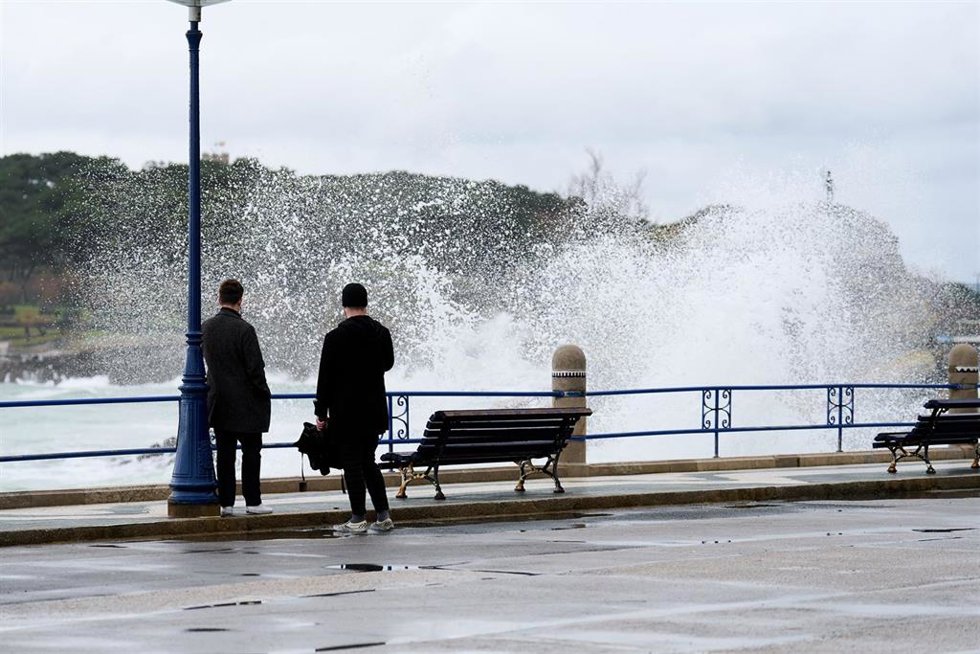 Archivo - Dos personas observan el oleaje en el puerto de Santander