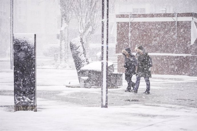 Dos personas caminan por una de las calles de Vitoria-Gasteiz tras la intensa nevada caída sobre la ciudad, a 27 de febrero de 2023.