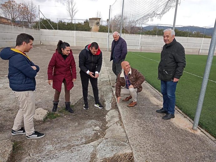 Hurtado (agachado) comprueba el estado del campo de fútbol de Alcolea.