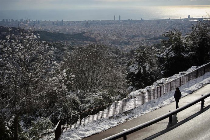 Una persona observa la vegetación cubierta de nieve en la Sierra de Collserola vista desde el Tibidabo, a 27 de febrero de 2023, en Barcelona, Catalunya (España). La borrasca Juliette ha dejado hoy nevadas en cotas bajas en el litoral y prelitoral de la
