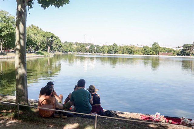 Archivo - Varias personas sentadas en la orilla del lago de la Casa de Campo.