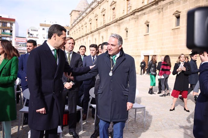 El presidente de la Junta de Andalucía Juanma Moreno saluda a el senador de su partido Elías Bendodoantes del comienzo del pleno institucional del Parlamento andaluz con motivo del Día de Andalucía.