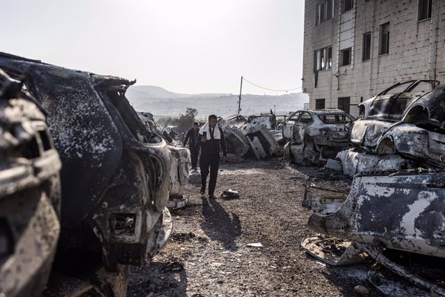 Varias personas inspeccionan los vehículos quemados en la ciudad cisjordana de Huwara después de que los colonos incendiaran casas y coches.
