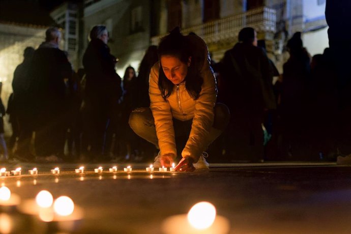 Una mujer coloca unas velas durante un minuto de silencio, ante el Ayuntamiento de Baiona, por el asesinato de una mujer, a 6 de febrero de 2023, en Baiona, Pontevedra, Galicia (España).
