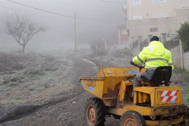 Archivo - Un trabajador pasa por un camino helado en Galicia.