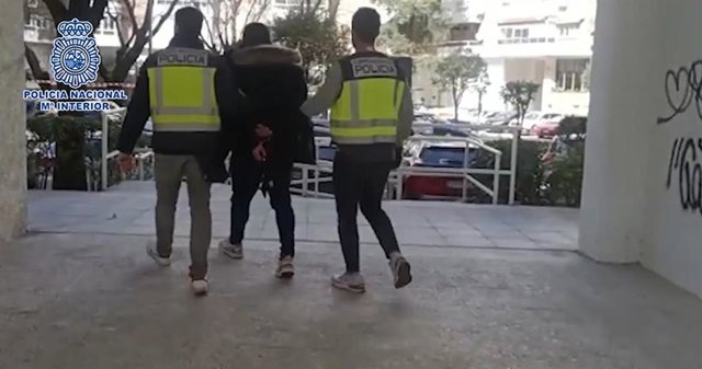 Agentes de la Policía Nacional custodian a uno de los arrestados.