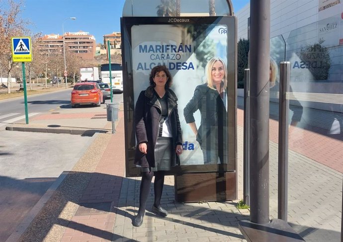 Elisa Cabrerizo, de UP en Granada, ante una marquesina con la imagen de Marifrán Carazo, del PP